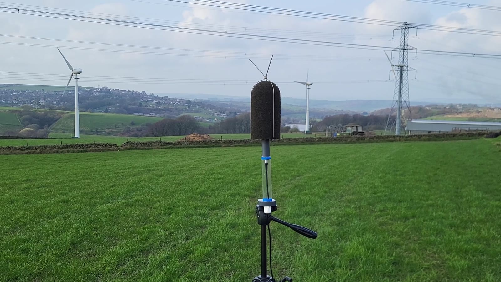Outdoor microphone with wind turbines and electricity infrastructure in the background