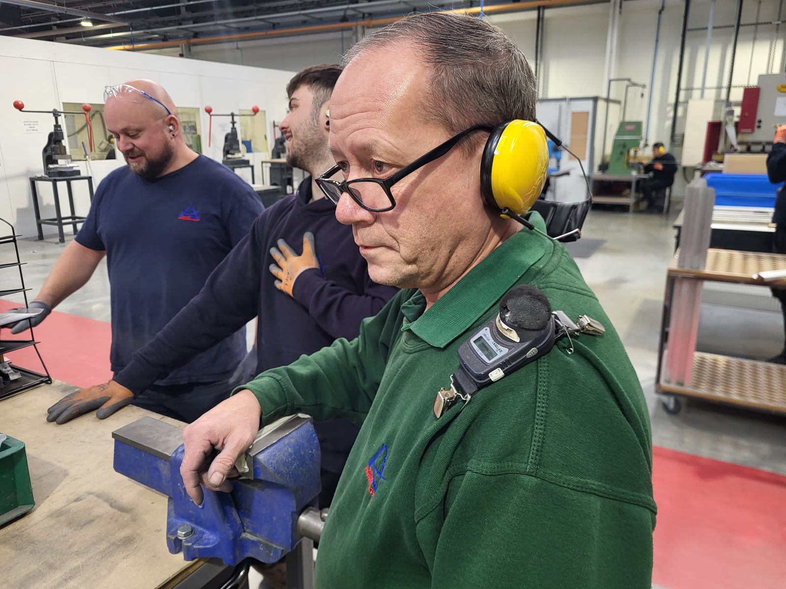 Workers wearing hearing protection and personal noise monitors